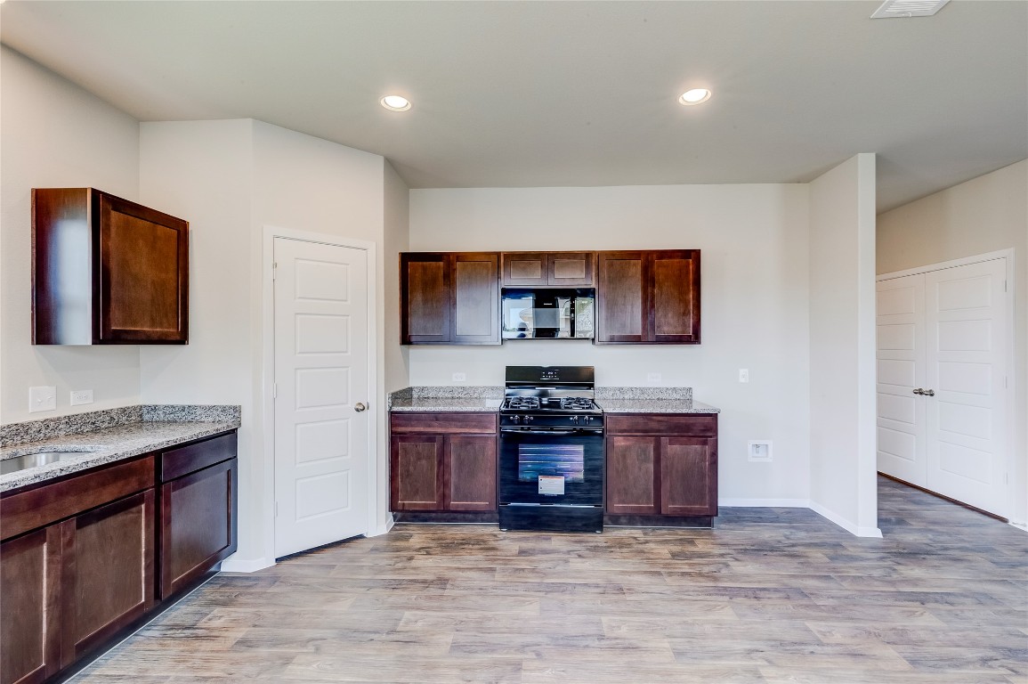 274 Jade Street Maxwell, TX 78656 - Photo 4 of 36 a view of kitchen with stainless steel appliances granite countertop a stove top oven a sink dishwasher and a refrigerator with wooden floor