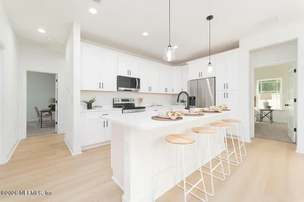 a kitchen with kitchen island a white counter top space a sink appliances and cabinets