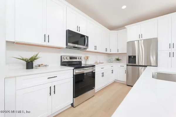 a kitchen with white cabinets and stainless steel appliances