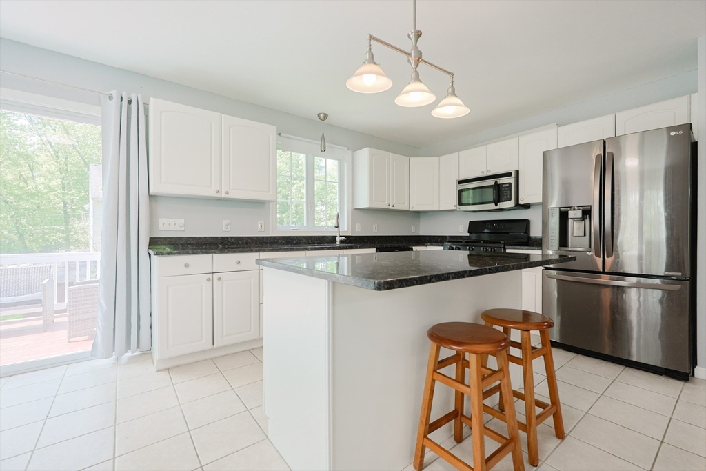38 Tavern Road Groton, MA 01450 - Photo 5 of 25 a kitchen with stainless steel appliances granite countertop a refrigerator a sink dishwasher a stove and white cabinets with wooden floor