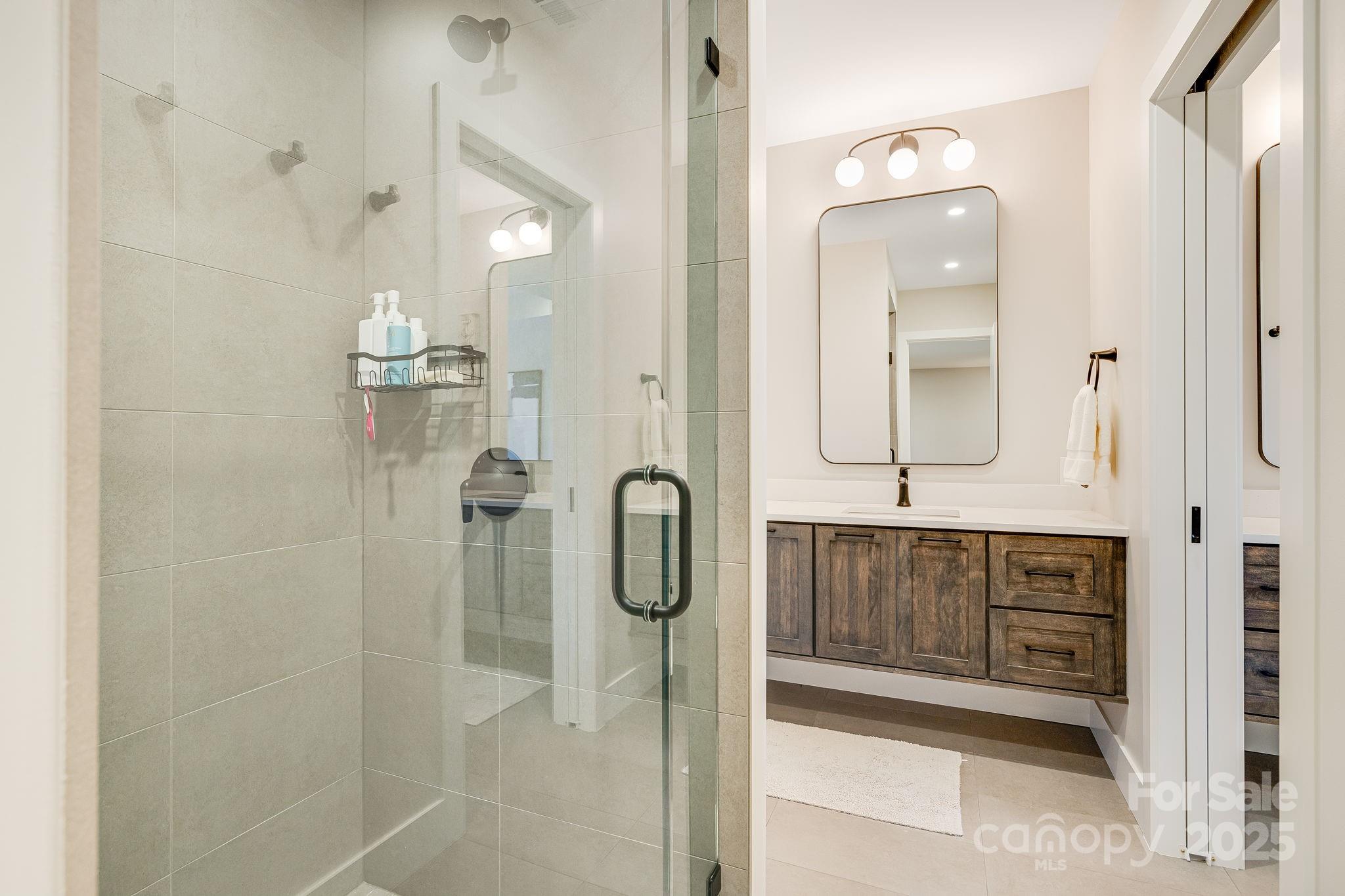 13 Switchgrass Way, Unit 407 Sylva, NC 28779 - Photo 29 of 48 a bathroom with shower a mirror a sink and vanity
