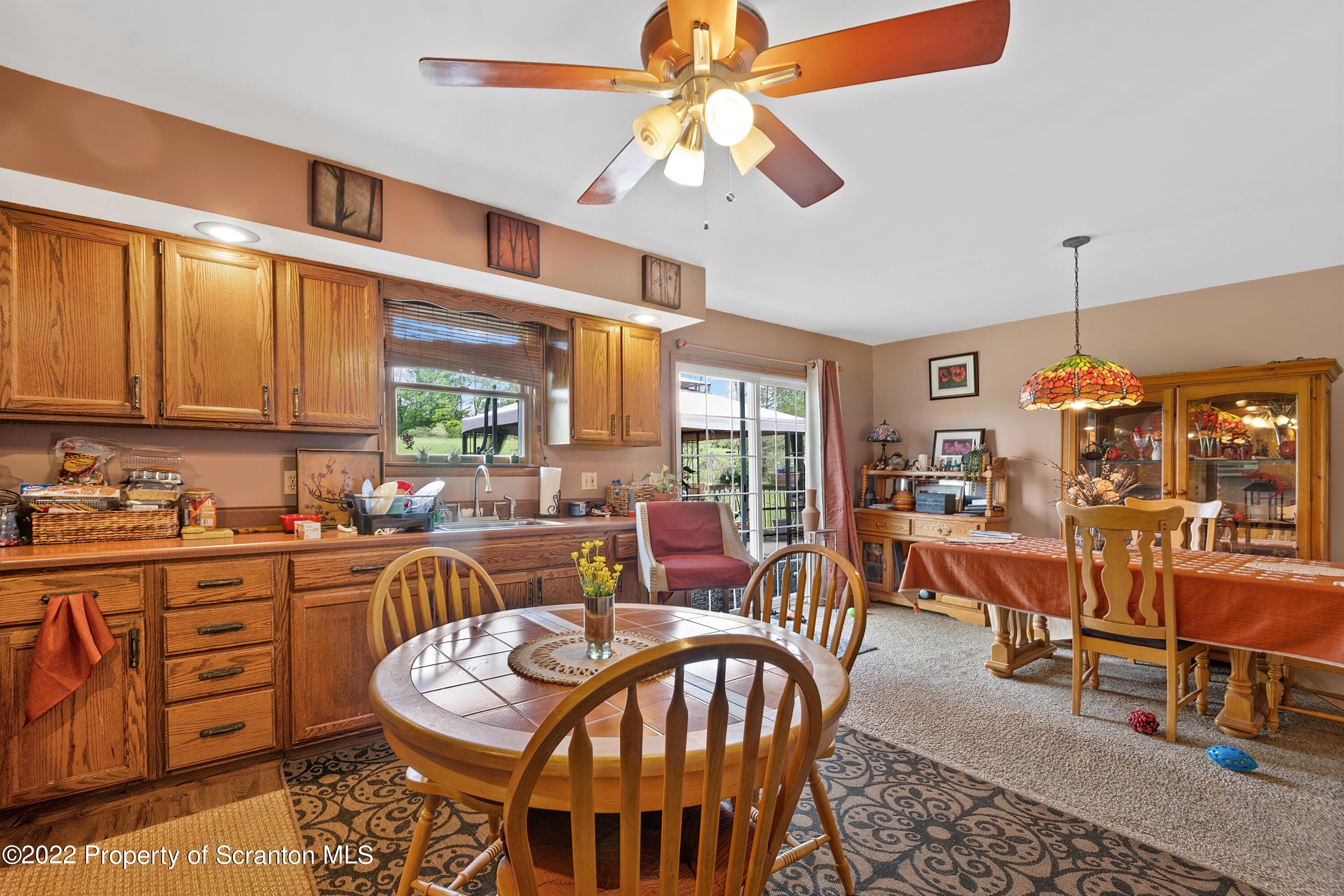 116 Hack Road Dalton, PA 18414 - Photo 17 of 33 a view of a dining room and livingroom with furniture wooden floor a rug a flat screen tv a rug and a chandelier