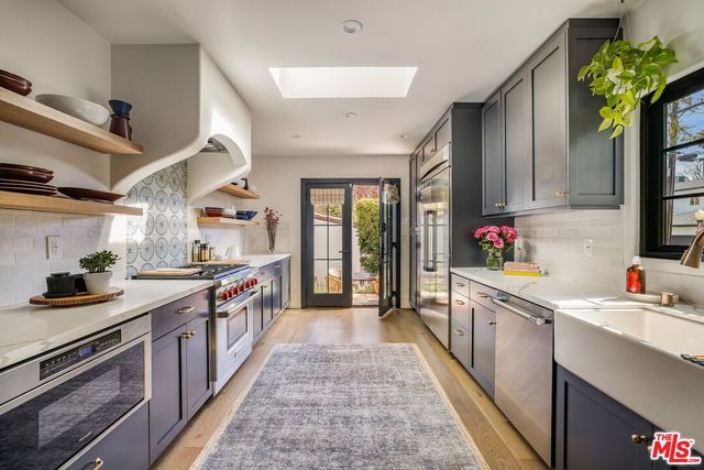 a kitchen with stainless steel appliances granite countertop a stove a sink dishwasher and cabinets with wooden floor