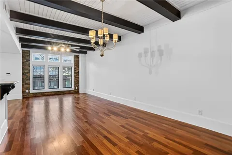 a view of an empty room with wooden floor and windows