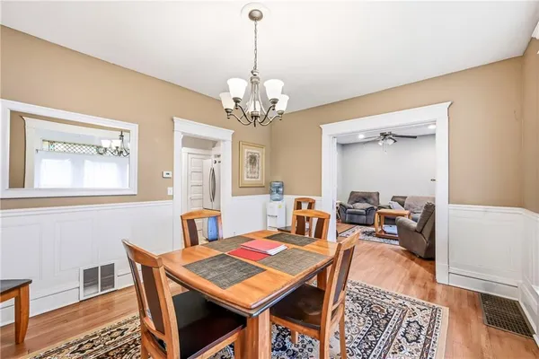 a dining room with wooden floor a chandelier a wooden table and chairs