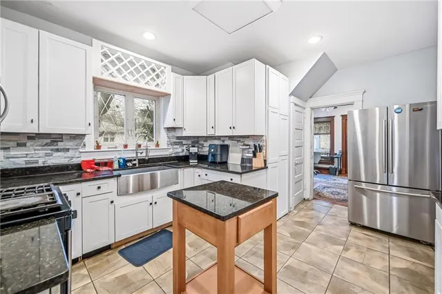 a kitchen with granite countertop a refrigerator stove top oven and sink
