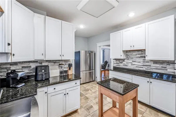a kitchen with stainless steel appliances granite countertop a stove a sink a refrigerator and white cabinets