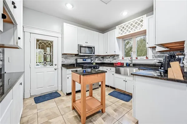a kitchen with granite countertop a stove a sink and a refrigerator
