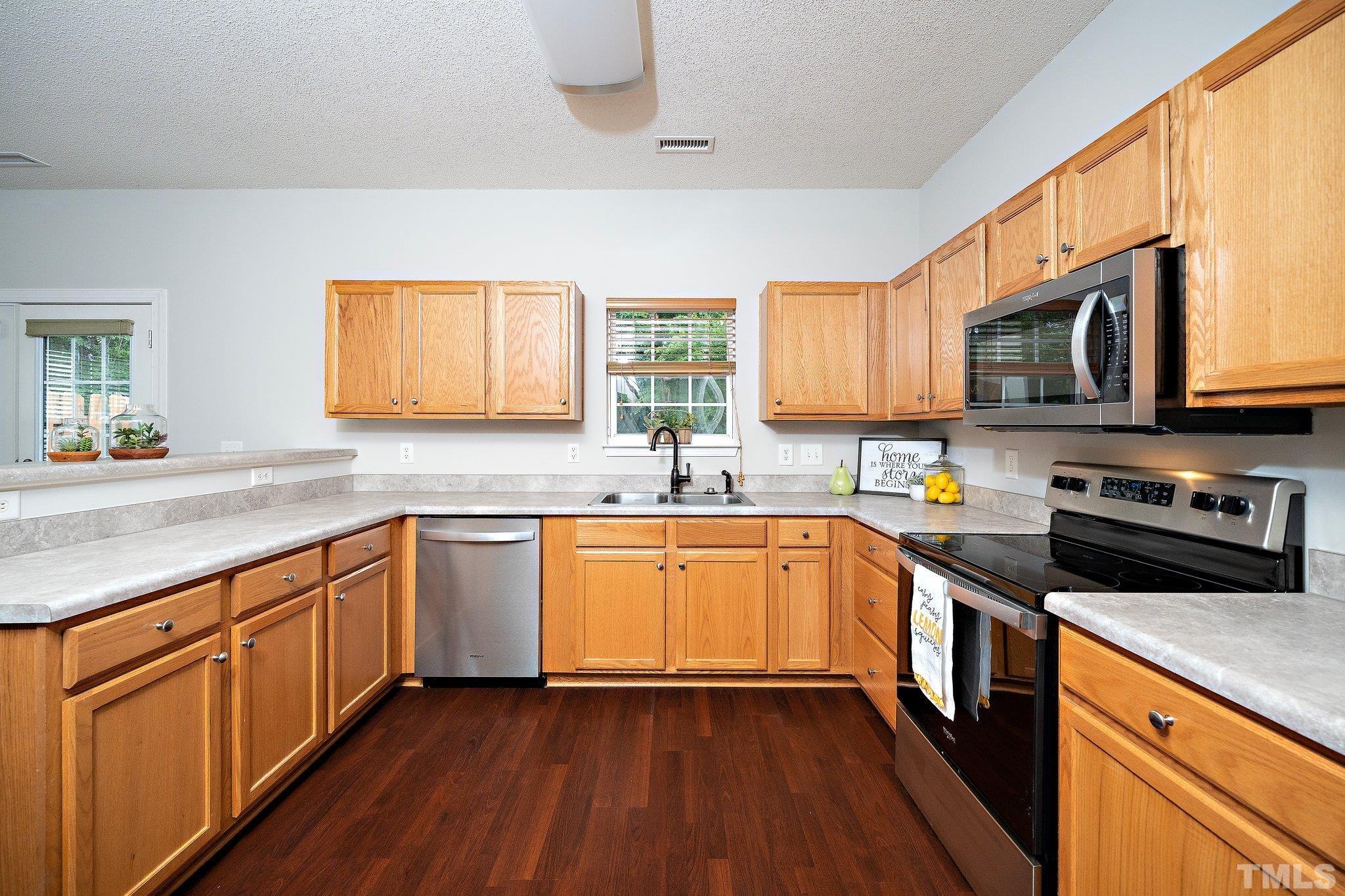 3121 Manhasset Lane Raleigh, NC 27604 - Photo 12 of 25 a kitchen with stainless steel appliances granite countertop wooden cabinets a stove top oven a sink and dishwasher with wooden floor