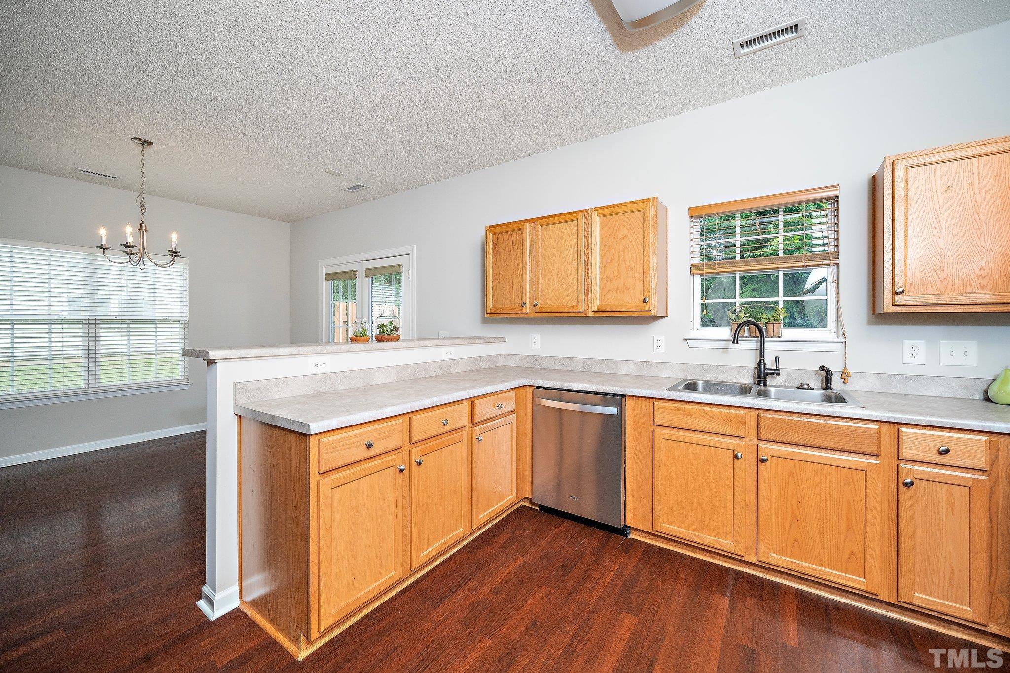 3121 Manhasset Lane Raleigh, NC 27604 - Photo 14 of 25 a kitchen with stainless steel appliances granite countertop a sink and dishwasher with wooden floor