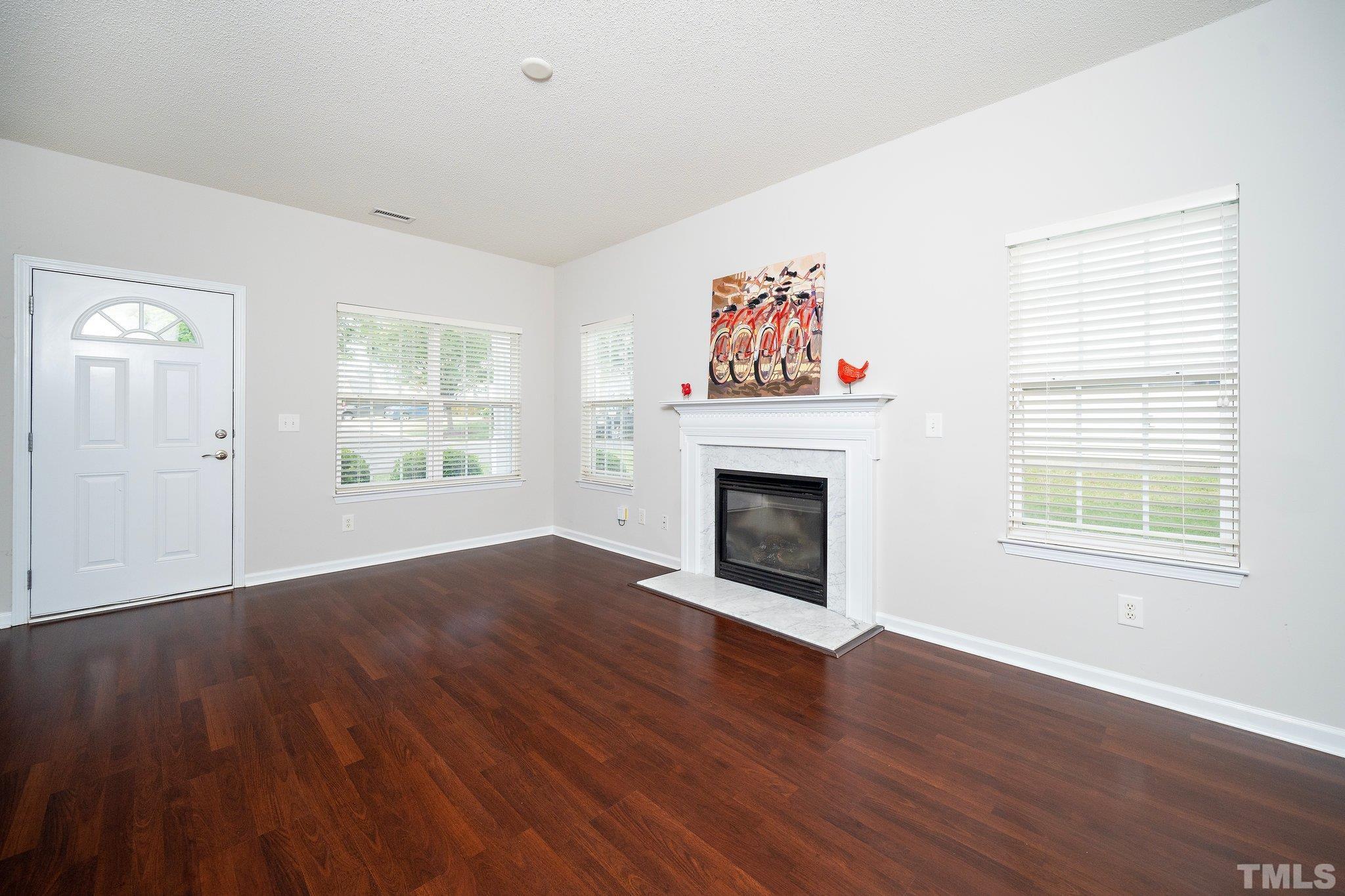 3121 Manhasset Lane Raleigh, NC 27604 - Photo 8 of 25 an empty room with windows fireplace and wooden floor