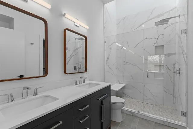 a bathroom with a double vanity sink toilet and shower
