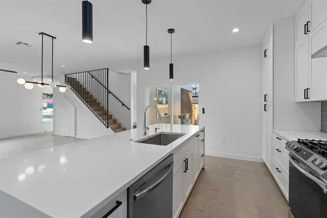 a kitchen with stainless steel appliances kitchen island granite countertop a sink a stove and a refrigerator