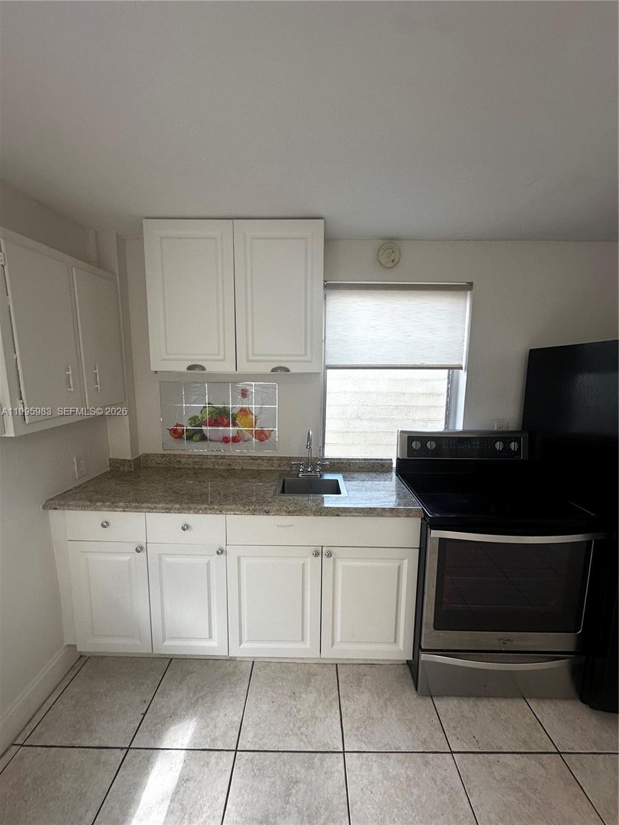 2420 Southwest 34th Avenue, Unit A Miami, FL 33145 - Photo 10 of 15 a kitchen with granite countertop a sink and a stove top oven