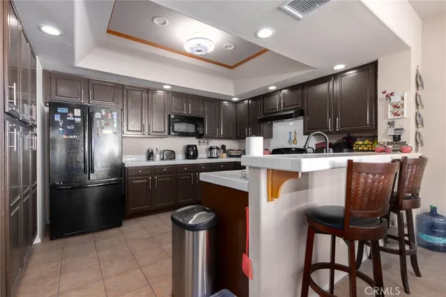 a kitchen with stainless steel appliances kitchen island granite countertop a refrigerator a stove a sink a microwave and a refrigerator