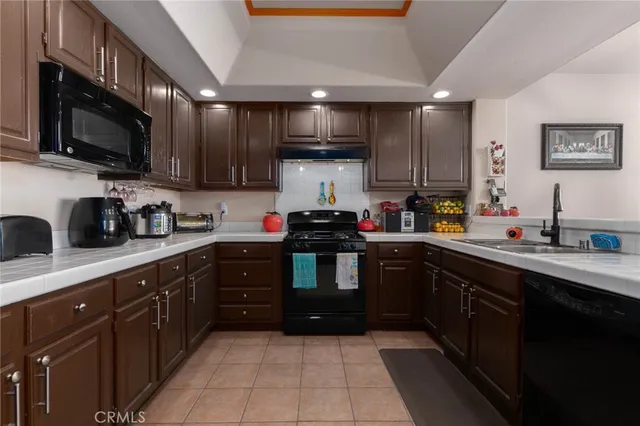 a kitchen with stainless steel appliances granite countertop a sink dishwasher stove top oven and refrigerator with wooden cabinets
