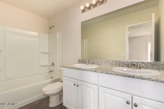 a bathroom with a granite countertop sink toilet mirror and bathtub