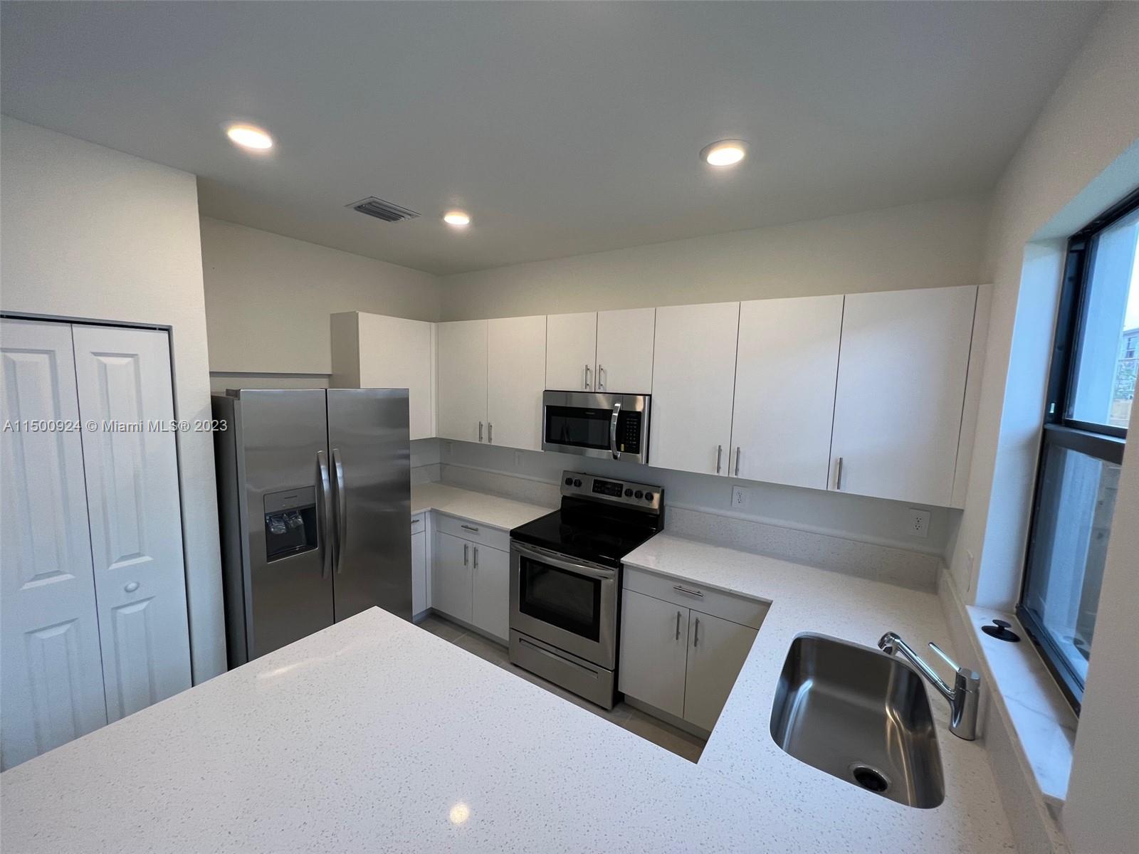11743 Southwest 246th Terrace, Unit 11743 Homestead, FL 33032 - Photo 4 of 10 a kitchen with a refrigerator sink and stove