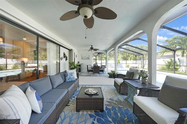 a living room with furniture ceiling fan and a large window