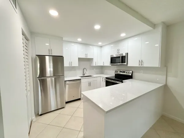 a kitchen with a sink a refrigerator a microwave and cabinets