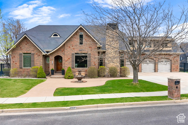 View of front of home with a garage, a front yard, brick siding, and driveway