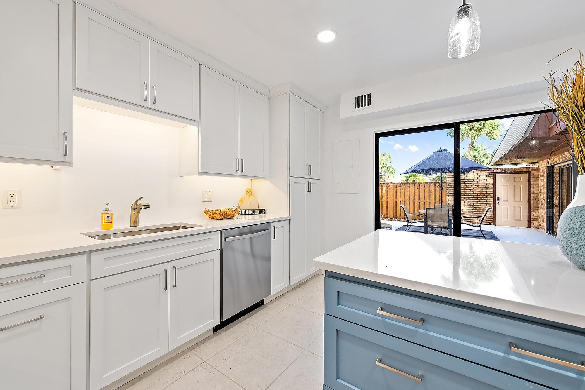 1420 Ocean Way, Unit 30C Jupiter, FL 33477 - Photo 7 of 25 a kitchen with granite countertop white cabinets and white appliances