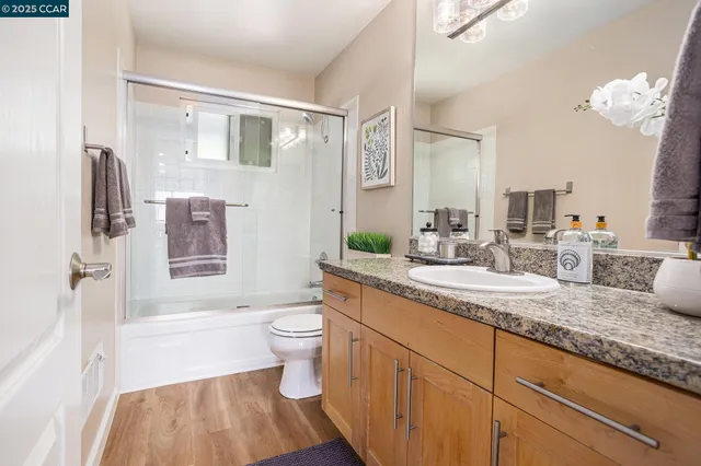 a bathroom with a granite countertop sink toilet a large mirror a bathtub and shower