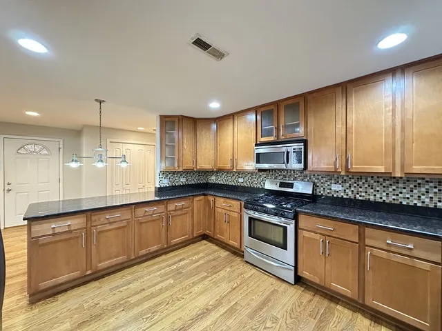 a kitchen with stainless steel appliances granite countertop wooden cabinets a stove top oven a sink and dishwasher
