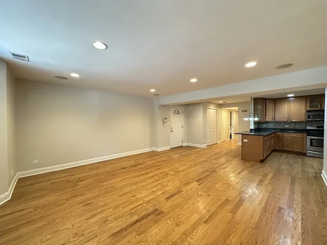 a view of a kitchen with kitchen island a sink wooden floor and black appliances