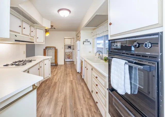 a kitchen with stainless steel appliances a stove top oven a sink a counter space and cabinets