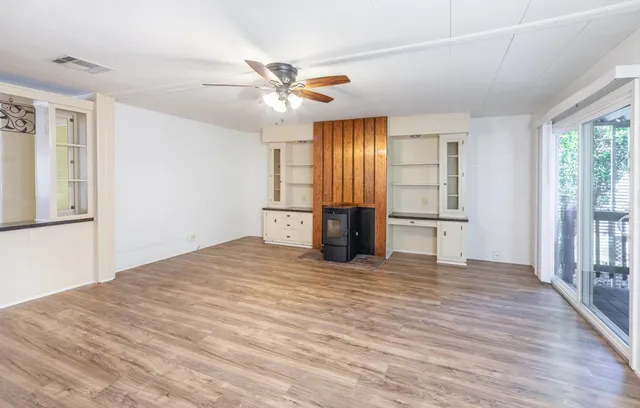 a view of an empty room with window and wooden floor