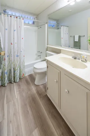 a view of a hallway with wooden floor and a bathroom