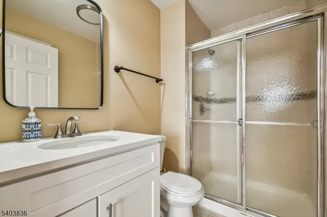 a bathroom with a shower sink vanity mirror and toilet