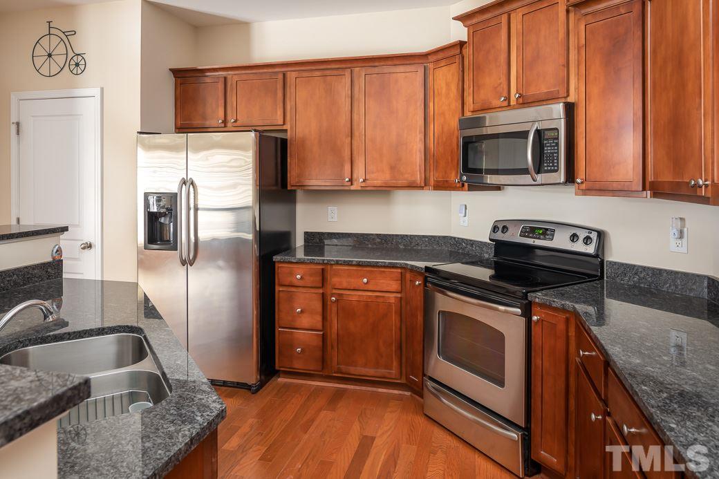 1345 Still Monument Way Raleigh, NC 27603 - Photo 6 of 28 a kitchen with granite countertop stainless steel appliances a stove a sink and a microwave