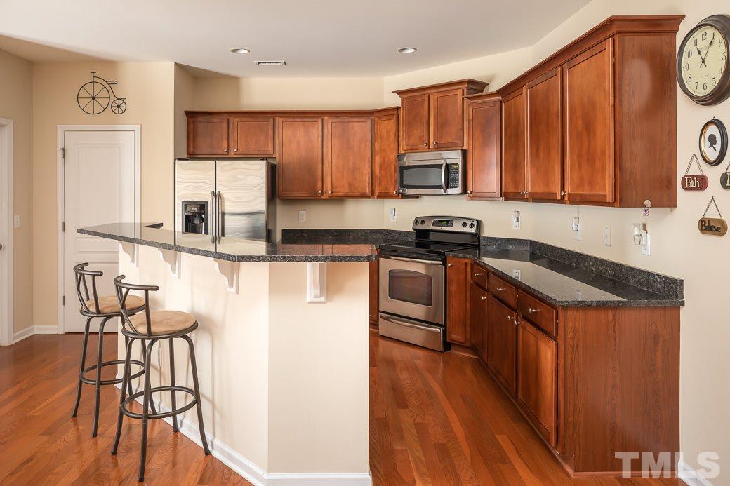 1345 Still Monument Way Raleigh, NC 27603 - Photo 7 of 28 a kitchen with stainless steel appliances granite countertop a stove a sink dishwasher and a refrigerator with wooden floor
