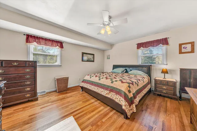 a bedroom with a bed and dresser with wooden floor