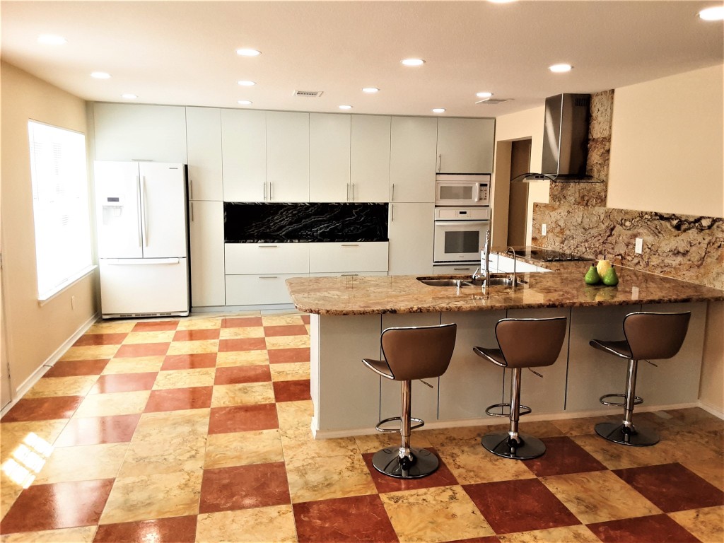 205 Rinehardt Street Hutto, TX 78634 - Photo 14 of 40 a kitchen with stainless steel appliances kitchen island granite countertop a stove a sink and a refrigerator