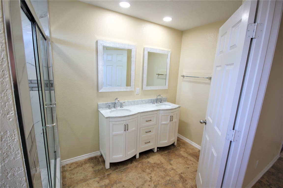 205 Rinehardt Street Hutto, TX 78634 - Photo 19 of 40 a bathroom with a granite countertop sink a mirror and a shower