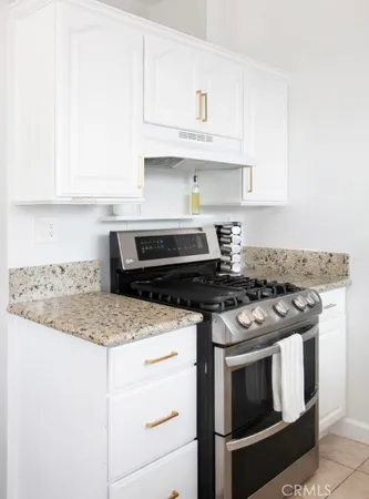 a kitchen with granite countertop white cabinets and stainless steel appliances
