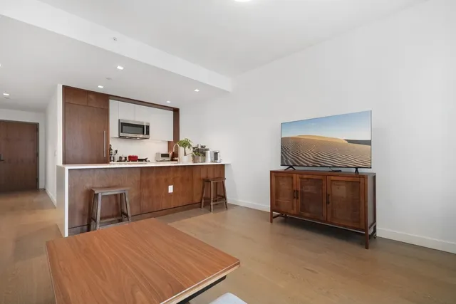 a living room with furniture a flat screen tv and kitchen view