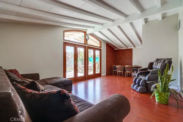 a living room with furniture hard wood floor and a floor to ceiling window