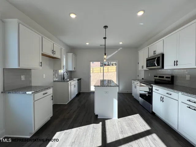 a kitchen with cabinets stainless steel appliances a sink and a window
