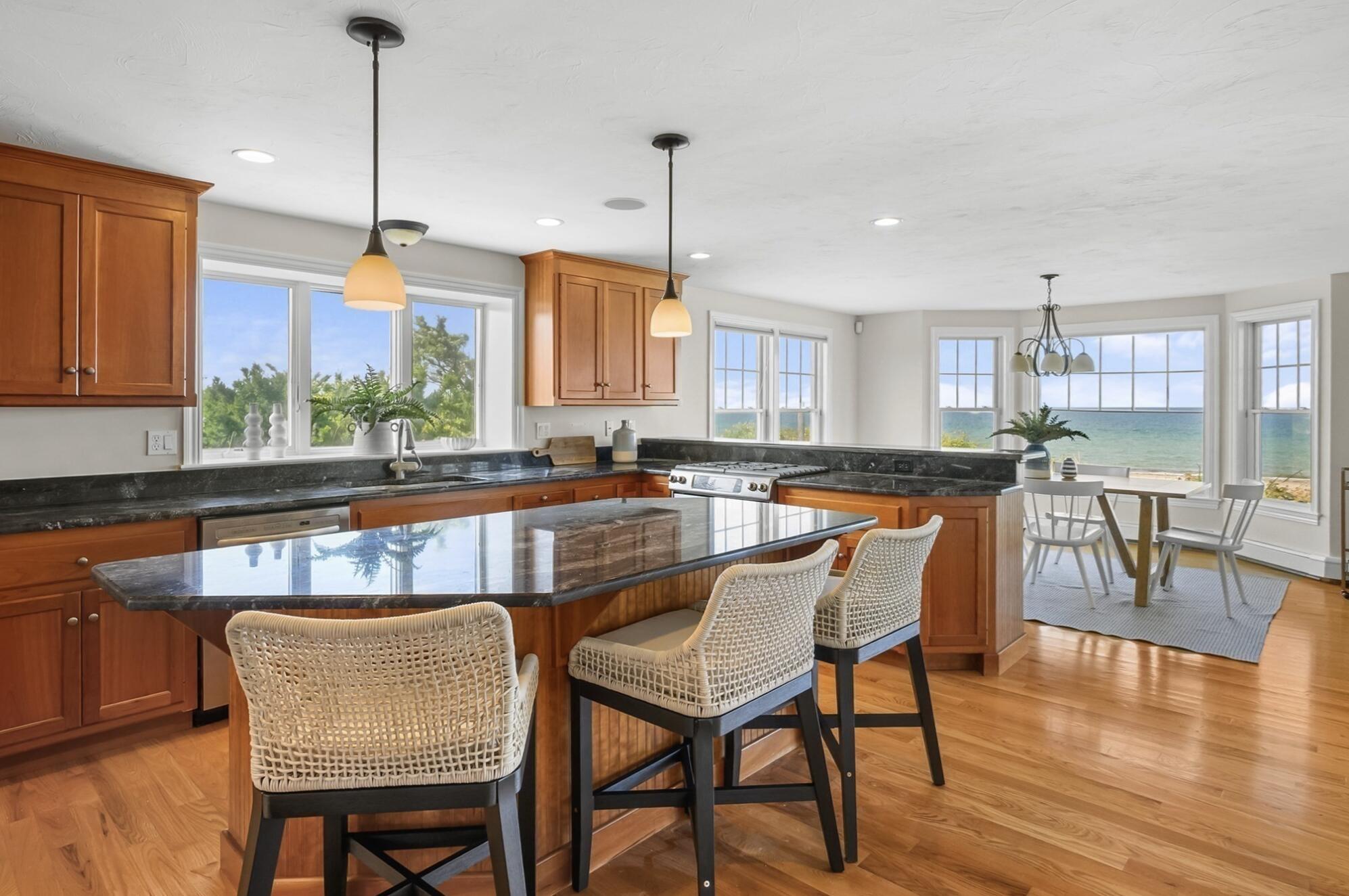 67 Phillips Road Sagamore Beach, MA 02562 - Photo 12 of 34 a kitchen with stainless steel appliances granite countertop a stove a sink a refrigerator a dining table and chairs with wooden floor