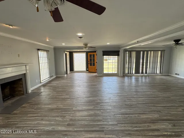a view of an empty room with wooden floor and a fireplace