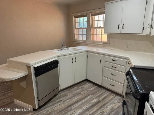 a kitchen with cabinets appliances a sink and a window