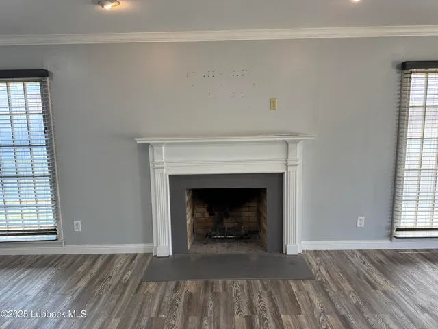 a view of an empty room with wooden floor fireplace and a window
