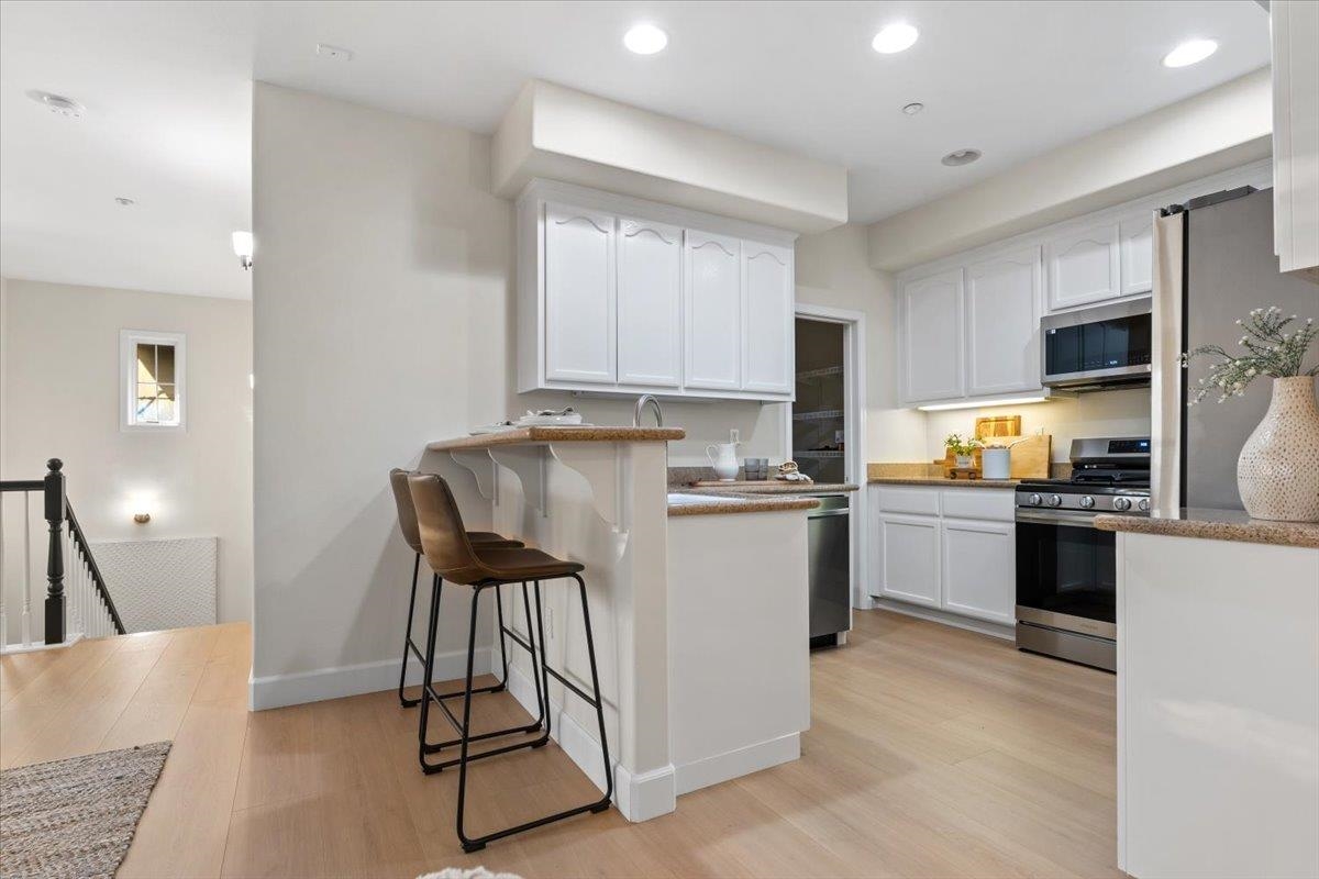 3251 Monaghan Street Dublin, CA 94568 - Photo 22 of 56 a kitchen with a refrigerator a stove top oven a sink dishwasher and white cabinets with wooden floor