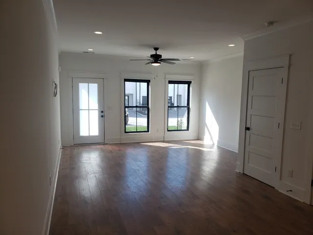 an empty room with wooden floor chandelier and windows