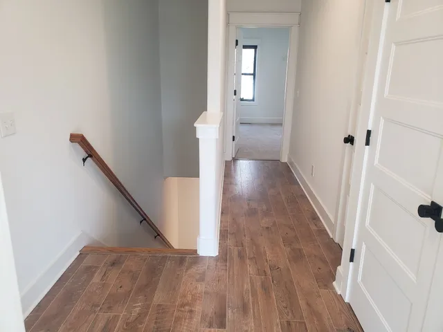 a view of a hallway with wooden floor and staircase