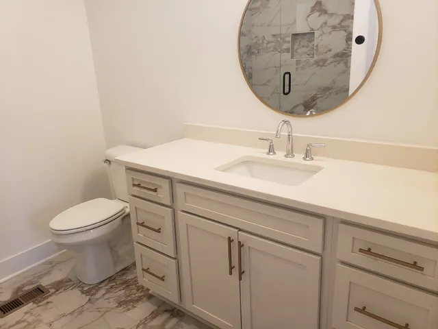 a bathroom with a granite countertop toilet sink mirror and vanity
